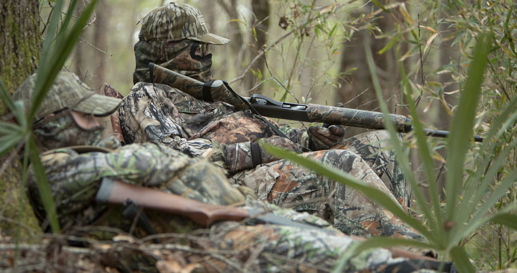 Two Alabama turkey hunters sitting against a tree.